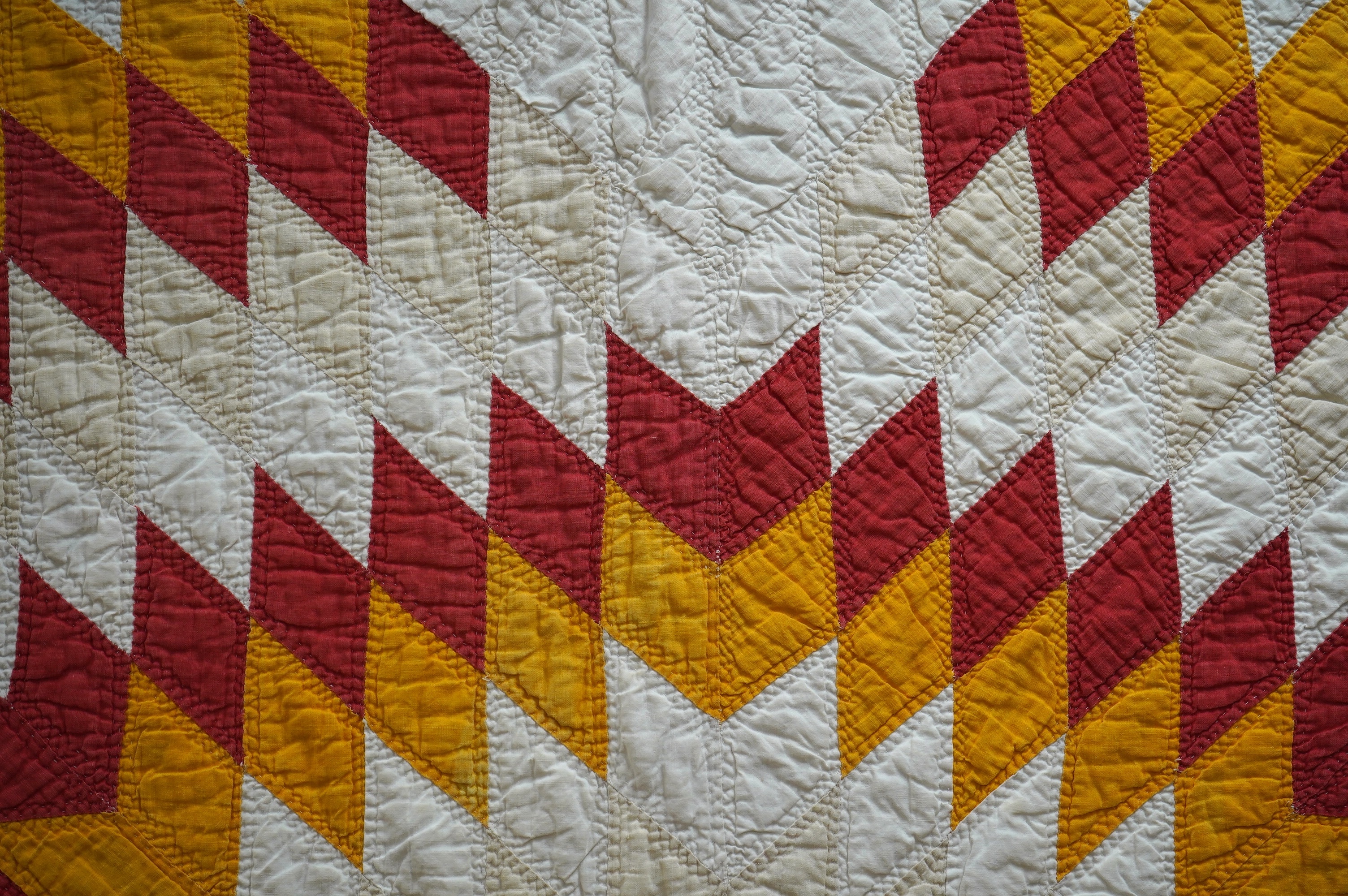 A late 19th century / early 20th century American ‘Star of Bethlehem’ quilt, worked on a plain light cream ground with red and yellow and beige patchworks forming a large double line star with a simple single red inner l